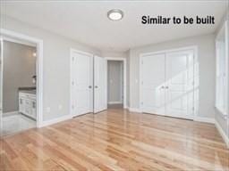 unfurnished bedroom featuring ensuite bathroom, wood finished floors, and baseboards