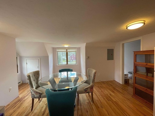 dining room featuring light wood finished floors, a baseboard heating unit, and electric panel
