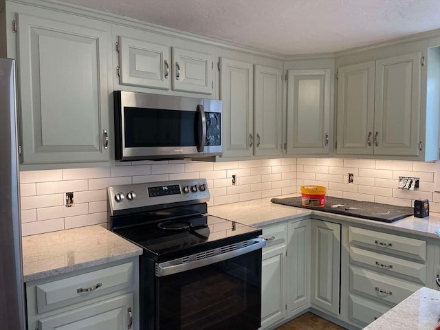kitchen with appliances with stainless steel finishes, backsplash, and light stone countertops