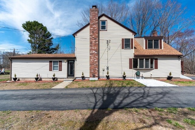 traditional-style home with roof with shingles and a chimney