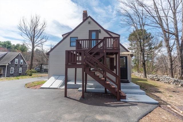 exterior space featuring a deck, a chimney, and stairs