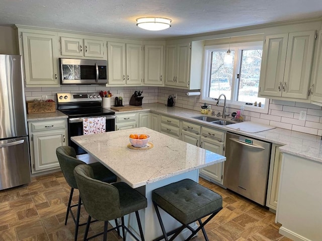 kitchen featuring a kitchen breakfast bar, appliances with stainless steel finishes, a sink, and tasteful backsplash