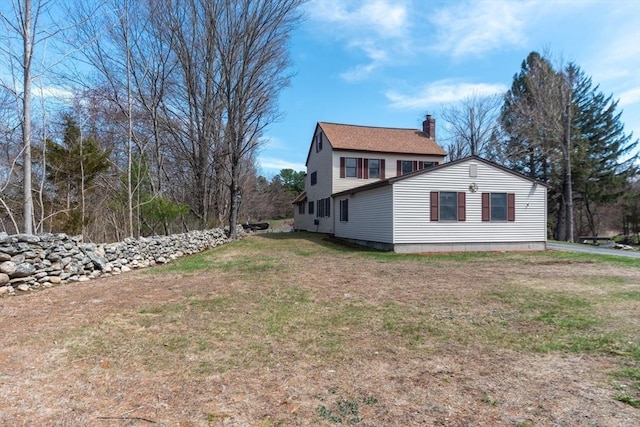 view of property exterior with a yard and a chimney