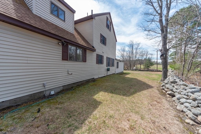view of side of property with a lawn and roof with shingles