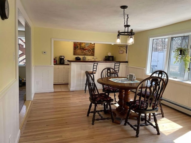 dining room featuring light wood finished floors and wainscoting