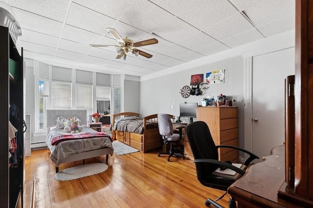 bedroom with baseboard heating, ceiling fan, a paneled ceiling, and hardwood / wood-style flooring