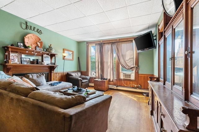 living room featuring light wood-style flooring, wainscoting, baseboard heating, and cooling unit