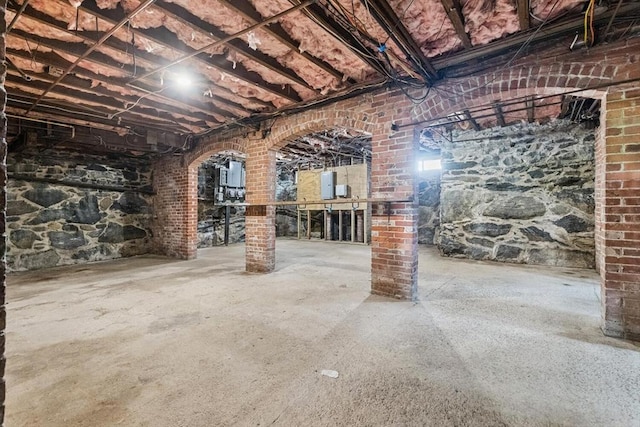 unfinished basement with arched walkways and electric panel