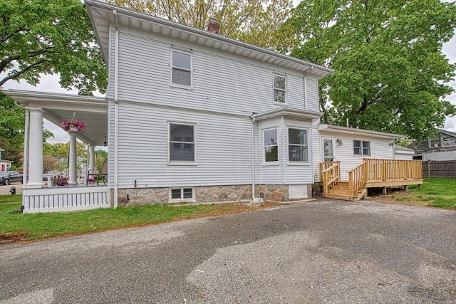 rear view of house featuring a chimney, covered porch, and a wooden deck