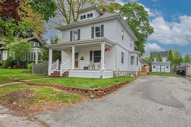 traditional style home with covered porch, a shed, an outdoor structure, and asphalt driveway