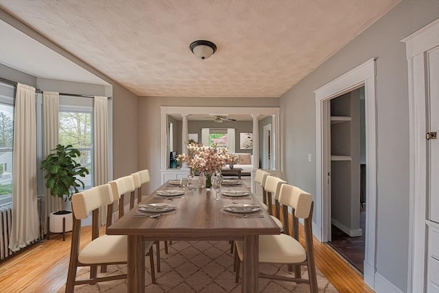 dining area with light wood-style flooring, a textured ceiling, ceiling fan, and baseboards