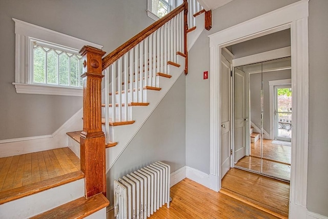 staircase featuring radiator heating unit, hardwood / wood-style floors, baseboards, and healthy amount of natural light
