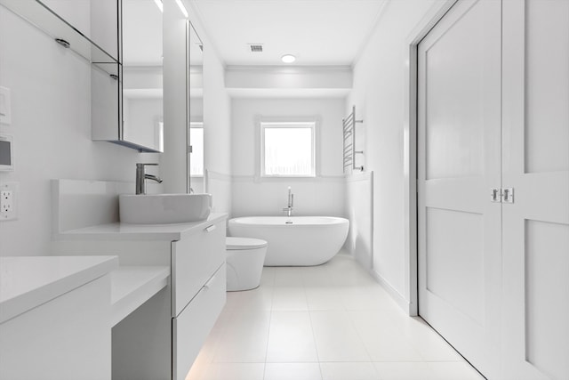 bathroom with a tub to relax in, vanity, crown molding, tile patterned flooring, and toilet