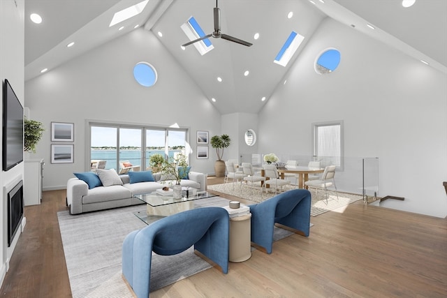 living room with a water view, ceiling fan, high vaulted ceiling, and light hardwood / wood-style floors