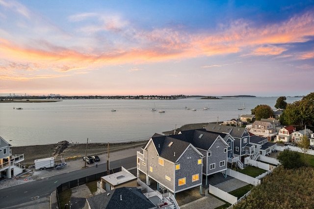 aerial view at dusk featuring a water view