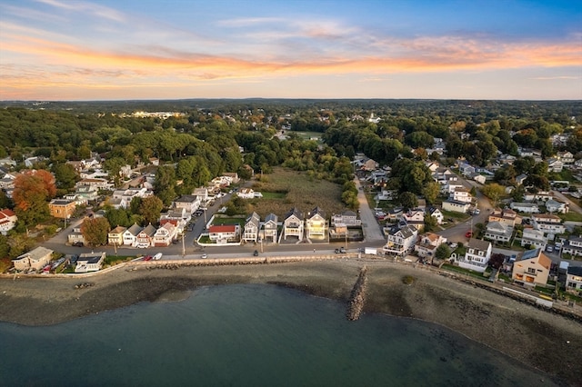 aerial view at dusk featuring a water view and a beach view