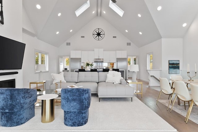 living room with hardwood / wood-style flooring, high vaulted ceiling, and a skylight