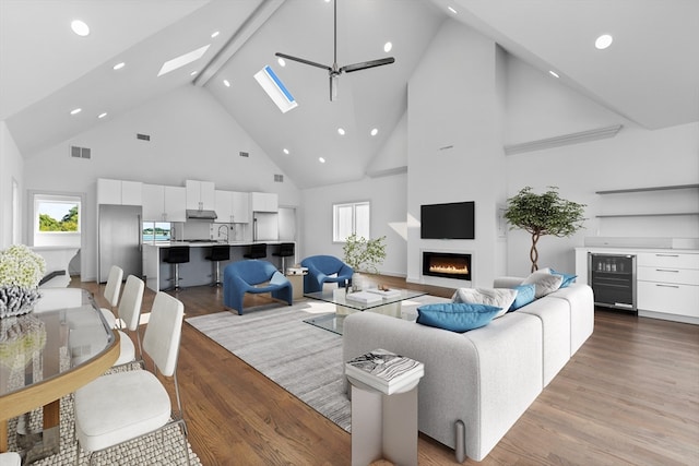 living room with ceiling fan, wine cooler, light hardwood / wood-style floors, and high vaulted ceiling