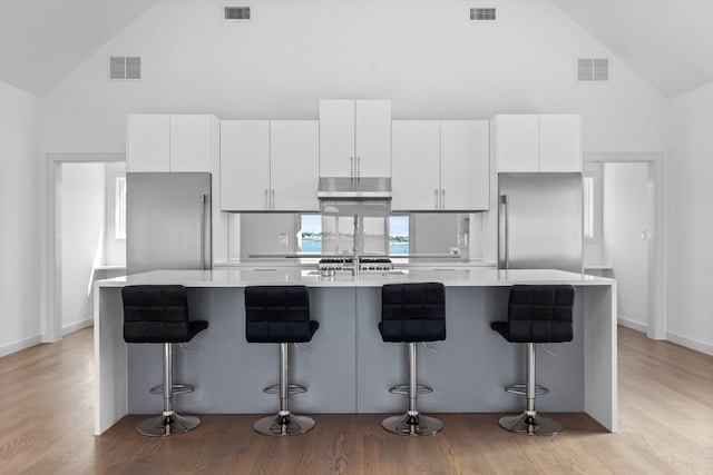 kitchen with a center island with sink, a breakfast bar, and white cabinetry