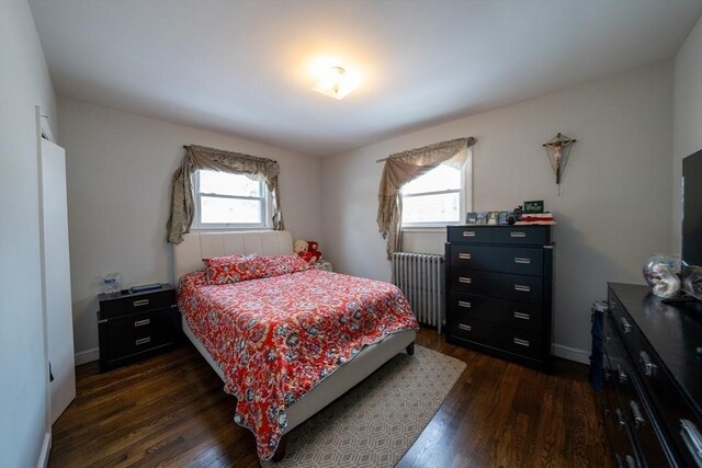 bedroom featuring dark wood-style flooring, radiator heating unit, and baseboards