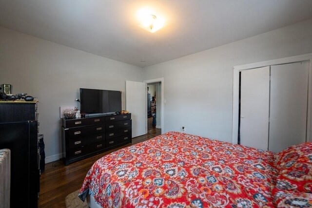 bedroom with a closet, dark wood finished floors, and baseboards