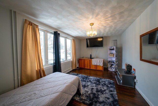 bedroom with baseboards, dark wood-style floors, baseboard heating, a textured ceiling, and a notable chandelier