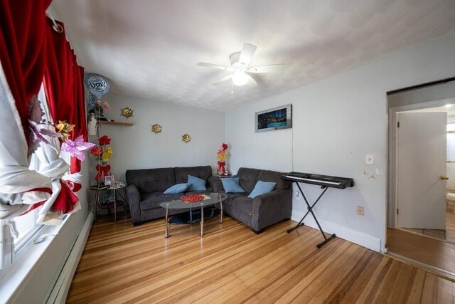 living room featuring light wood-style floors, baseboards, and a ceiling fan