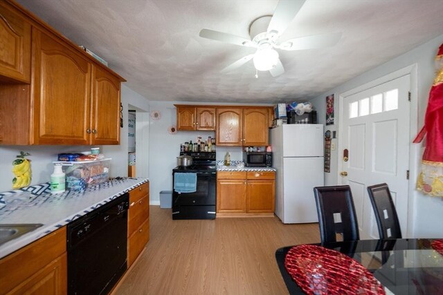 kitchen featuring ceiling fan, black appliances, brown cabinetry, and light wood-type flooring