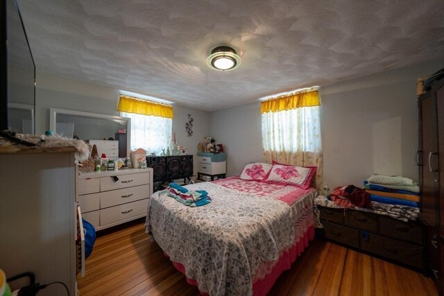 bedroom featuring multiple windows, a textured ceiling, and wood finished floors