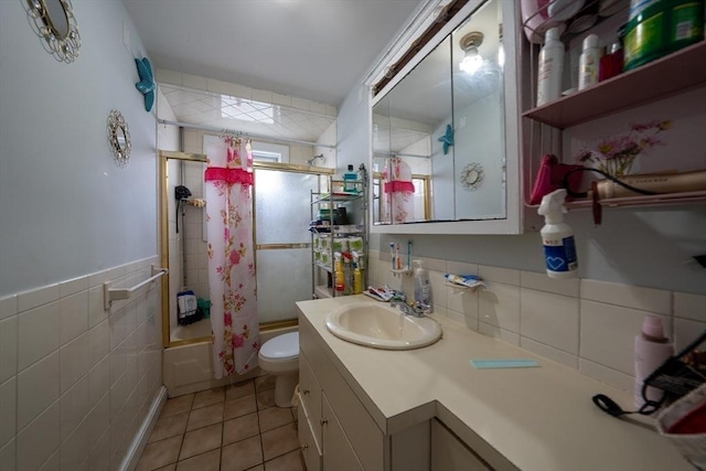 full bathroom with tile patterned flooring, toilet, shower / bath combination with glass door, vanity, and tile walls