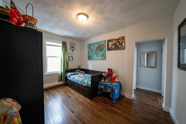 bedroom featuring a textured ceiling, baseboards, and wood finished floors