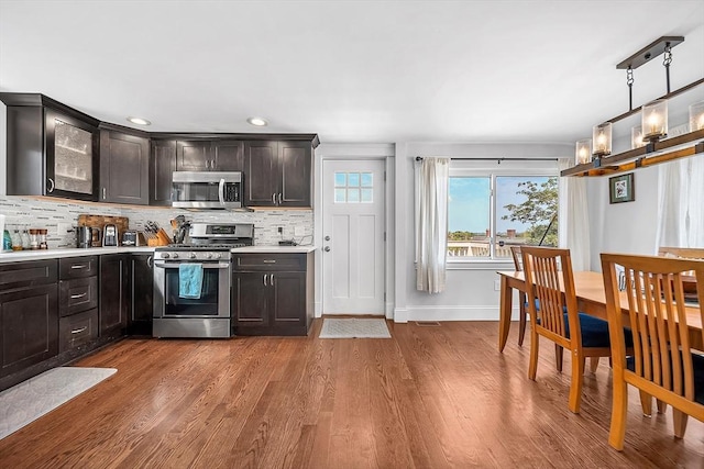 39 Madison St Unit 2, Somerville, MA 02143 - kitchen featuring appliances with stainless steel finishes, light countertops, backsplash, dark wood finished floors, and glass insert cabinets