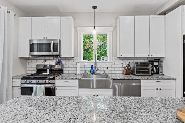 12 Russell St, Amesbury, MA 01913 - kitchen featuring appliances with stainless steel finishes, white cabinets, decorative backsplash, and light stone countertops