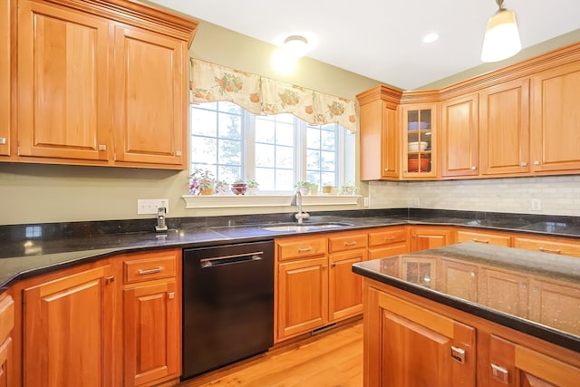 kitchen featuring black dishwasher, backsplash, light hardwood / wood-style flooring, dark stone countertops, and sink