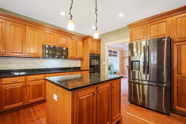 kitchen featuring a kitchen island, black appliances, decorative light fixtures, and light hardwood / wood-style floors