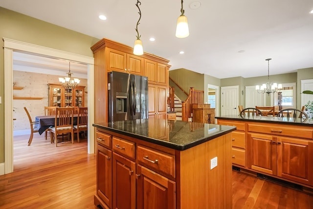 kitchen with dark hardwood / wood-style flooring, a kitchen island, stainless steel fridge with ice dispenser, a notable chandelier, and decorative light fixtures