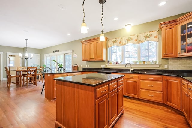 kitchen featuring light wood-type flooring, backsplash, a center island, pendant lighting, and a notable chandelier