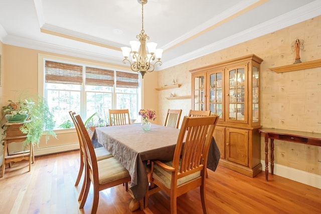 dining room with light hardwood / wood-style floors, ornamental molding, a chandelier, and a tray ceiling