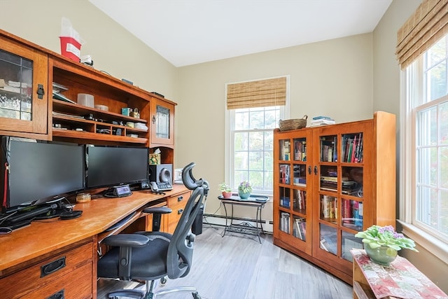 office area with a healthy amount of sunlight, light hardwood / wood-style flooring, and baseboard heating