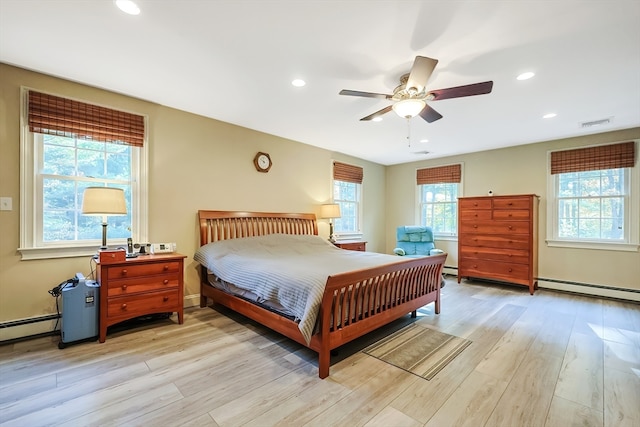 bedroom featuring a baseboard radiator, ceiling fan, multiple windows, and light wood-type flooring