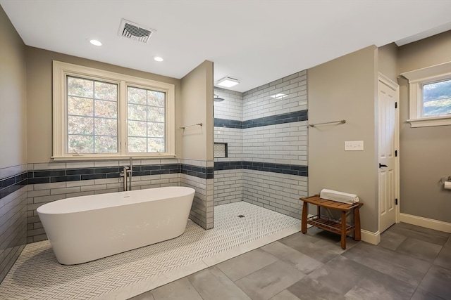 bathroom featuring tile walls, a wealth of natural light, and separate shower and tub