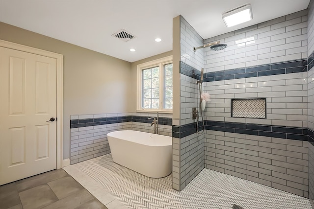 bathroom with tile walls, separate shower and tub, and tile patterned flooring