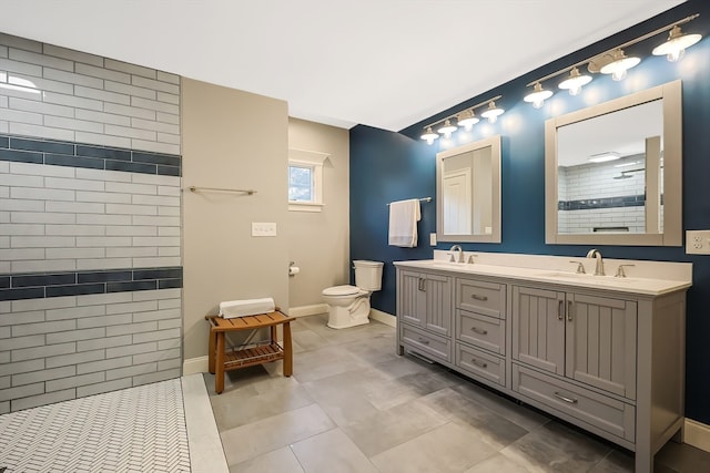 bathroom featuring vanity, a tile shower, toilet, and tile patterned flooring