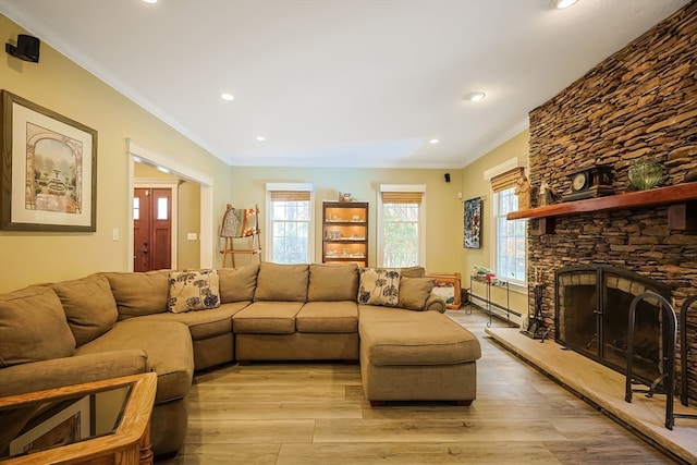 living room featuring ornamental molding, light hardwood / wood-style flooring, and a stone fireplace