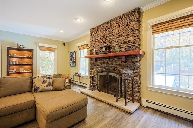 living room featuring light hardwood / wood-style floors, crown molding, a baseboard heating unit, and a fireplace