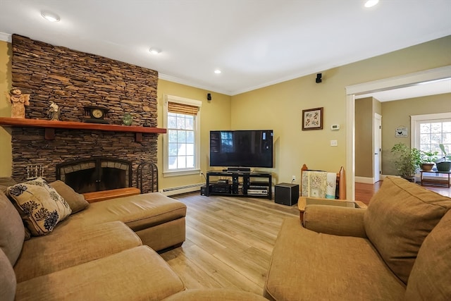 living room with light hardwood / wood-style flooring, a baseboard heating unit, a fireplace, and plenty of natural light