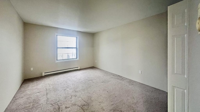 carpeted empty room featuring a baseboard heating unit