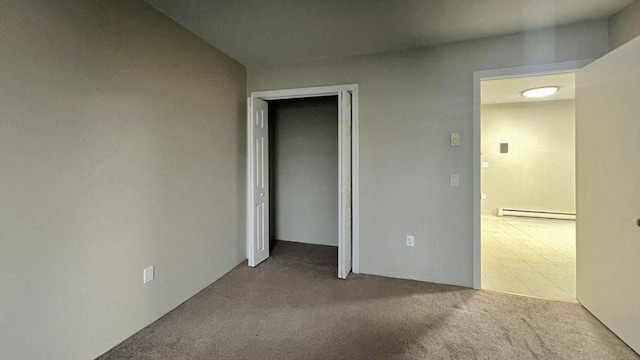 unfurnished bedroom with carpet floors, baseboard heating, and a closet