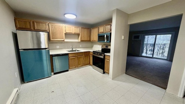 kitchen with baseboards, light countertops, a baseboard heating unit, a sink, and stainless steel appliances