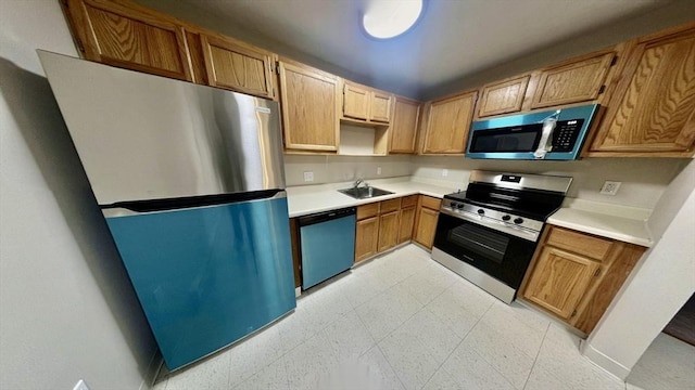 kitchen with light countertops, stainless steel appliances, a sink, and light floors